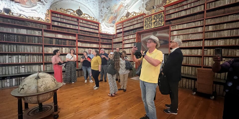 a group of people admiring a grand room with a painted ceiling