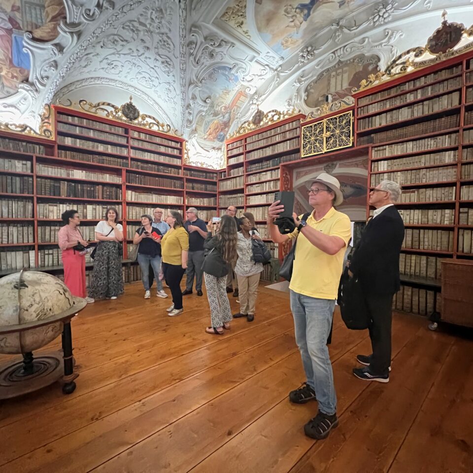 a group of people admiring a grand room with a painted ceiling