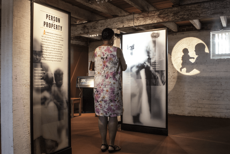 Woman looking at an exhibit describing the history of slavery. sharing histories