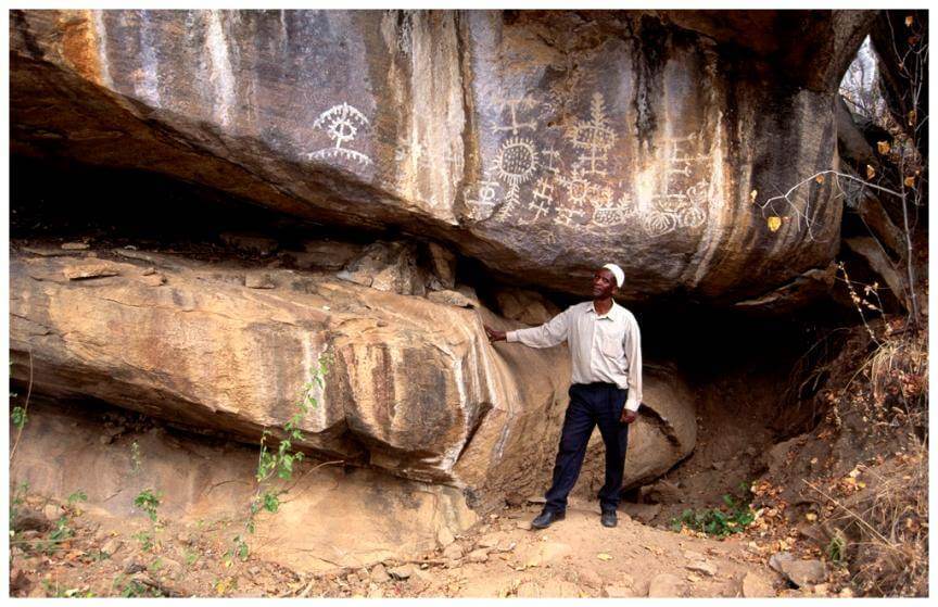 Overhanging boulders displaying ancient rock art with protected area