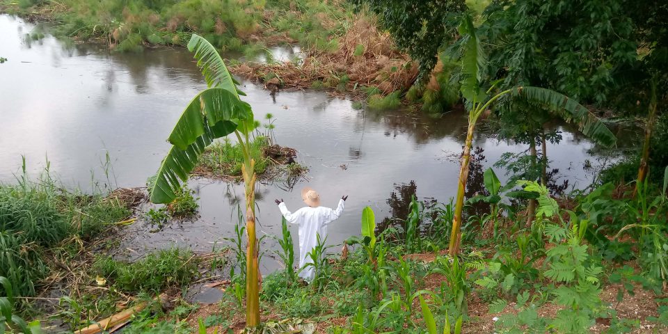 Ugandan heritage projects: The site keeper stands at the rising Nile river waters at Wang-lei