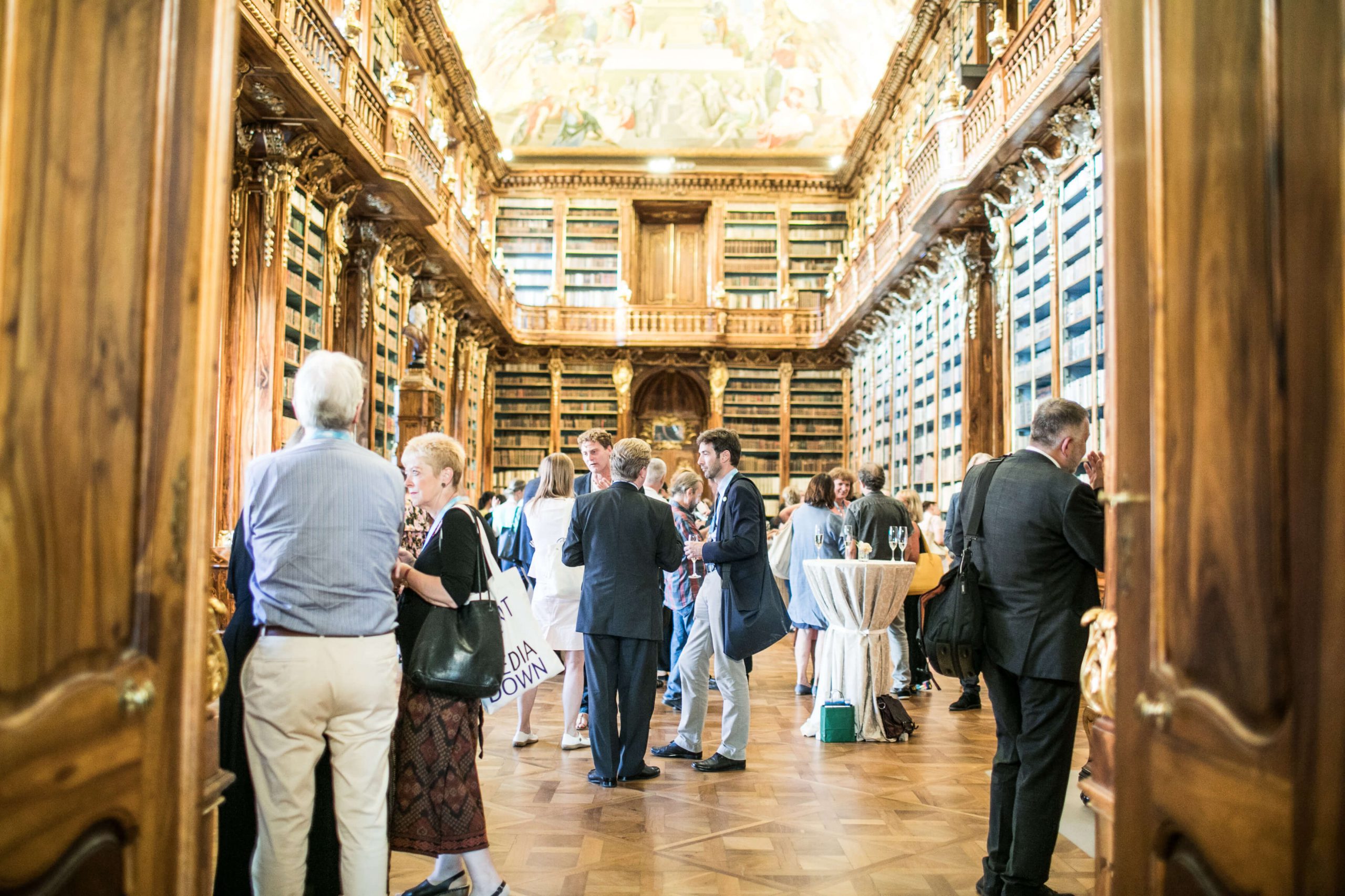 Picture of a grand library interior with groups of people talking