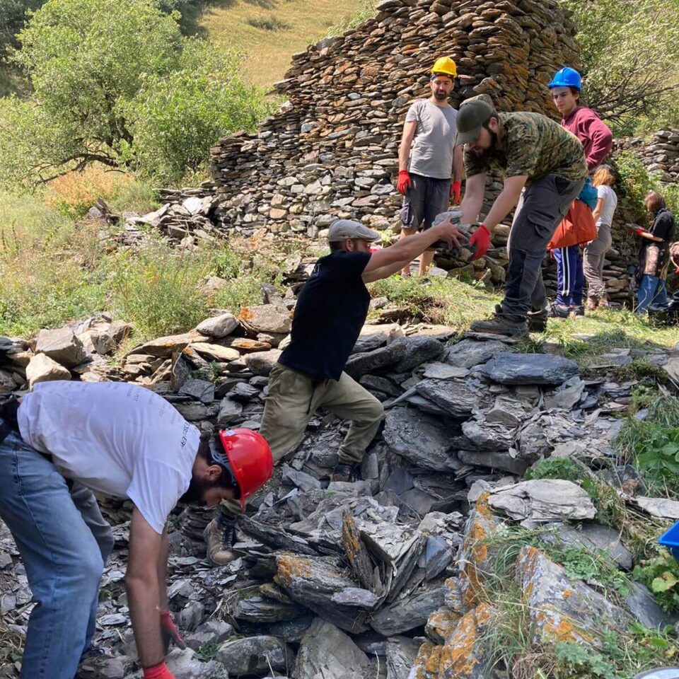 Volunteers work with REMPART expert to recover useable dry stones from tower base for its stabilisation