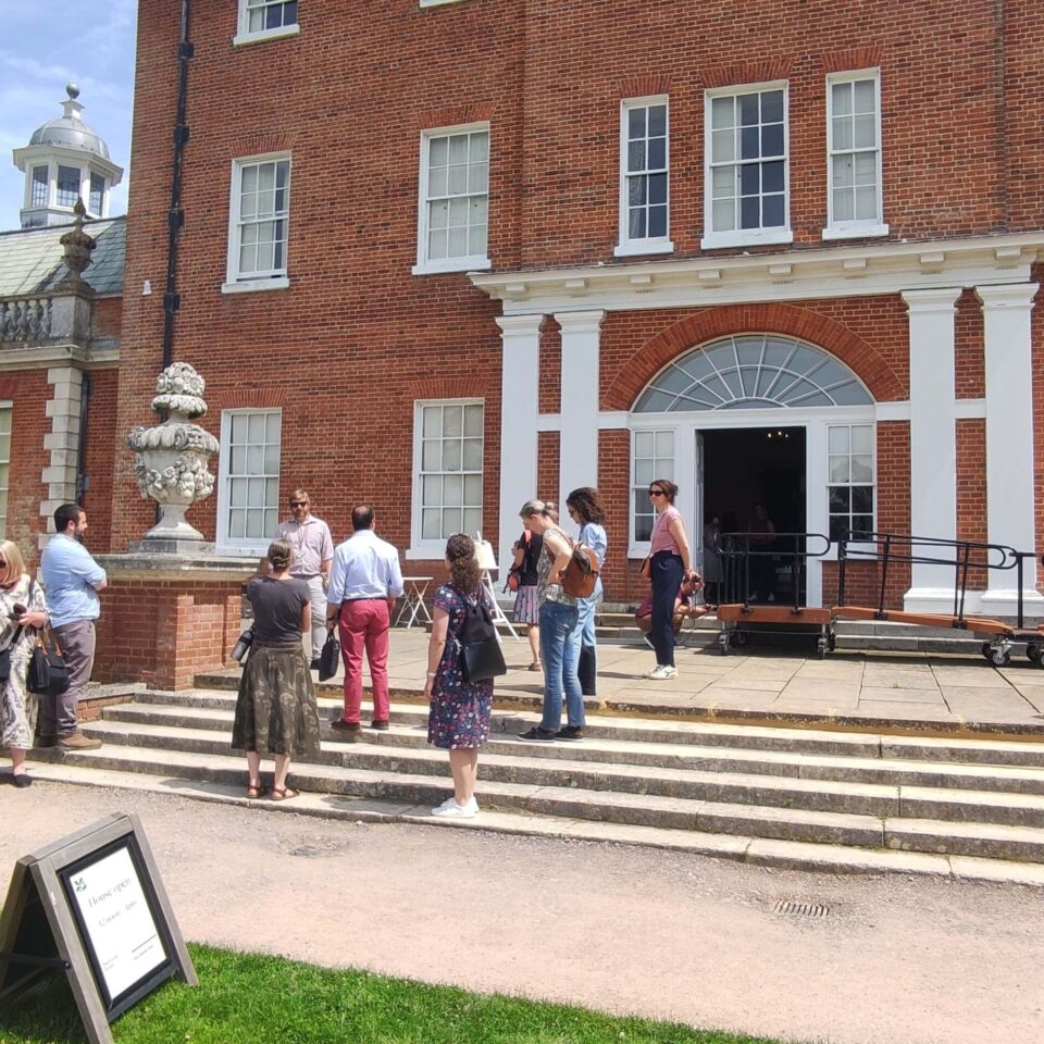 European group talking on the steps outside a grand house