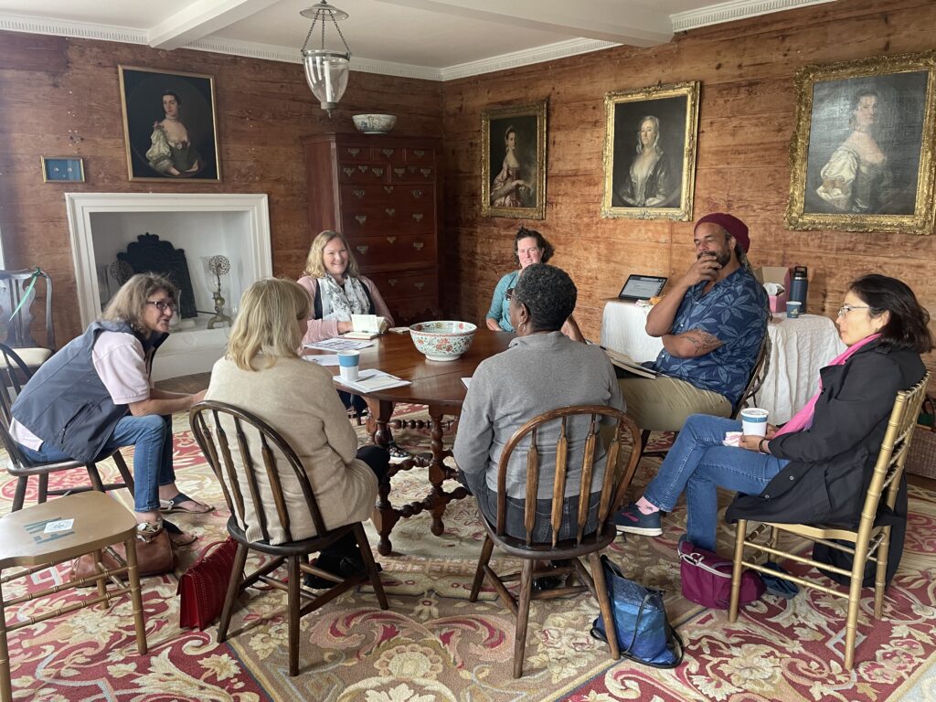 people sitting around a table in an historic room for a rise meeting