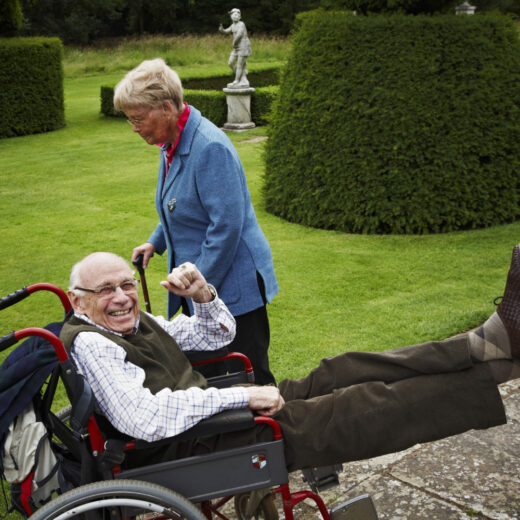 a man smiling in a wheelchair, using a wall to rest his feet broadening access