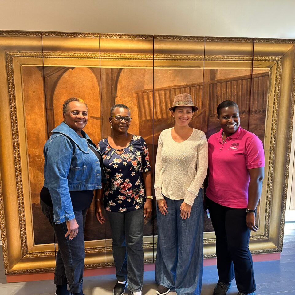 four women standing in front of a large painting