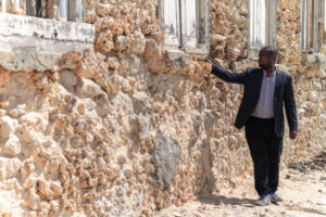 a man looking at a building with crumbling walls