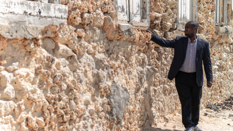 a man looking at a building with crumbling walls