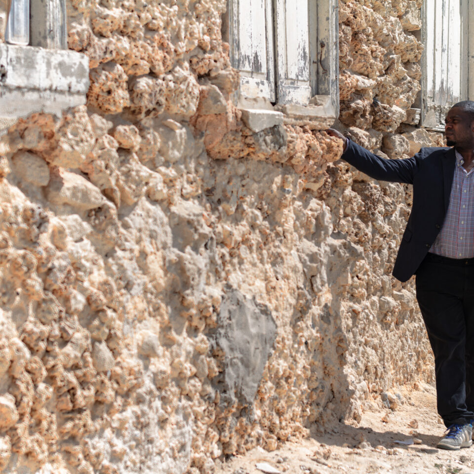 a man looking at a building with crumbling walls