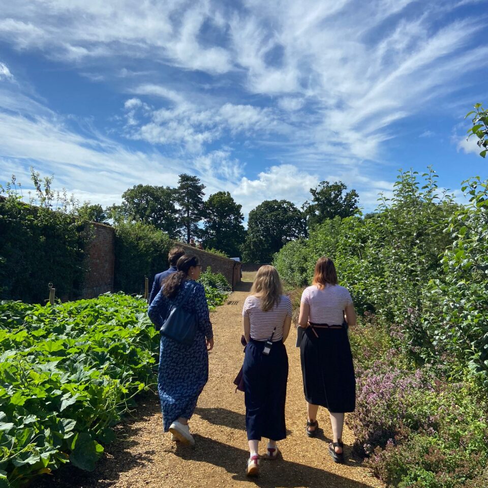 3 women walking and talking in a garden
