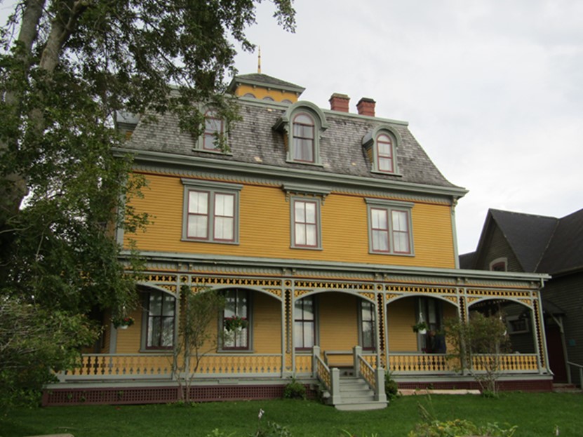 An historic house withe a veranda and vivid yellow walls