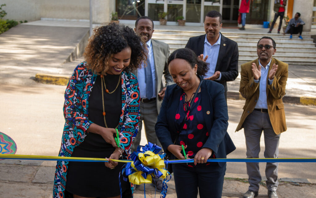 two women cutting a blue and yellow ribbon at an opening ceremony