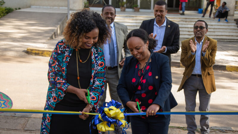 two women cutting a blue and yellow ribbon at an opening ceremony