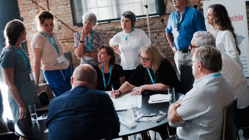 People standing and sitting around a table in an old building