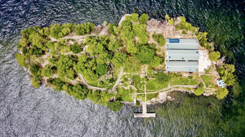 picture of a small island taken from above with green trees and blue sea