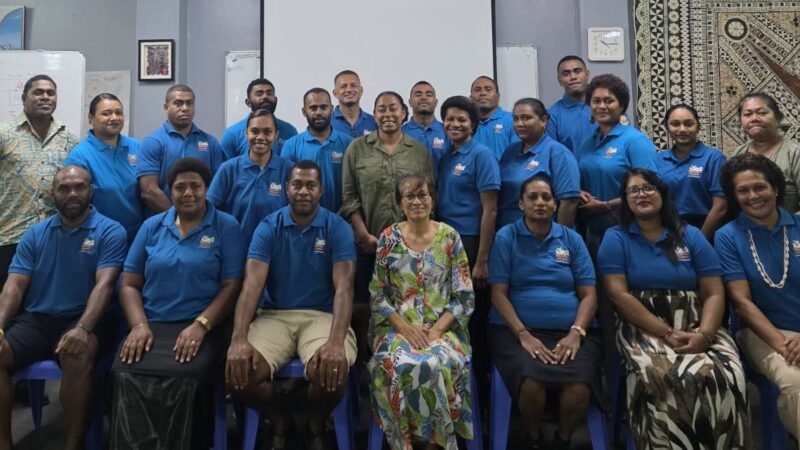 a group of people in bright blue polo shirts seated and smiling at the camera