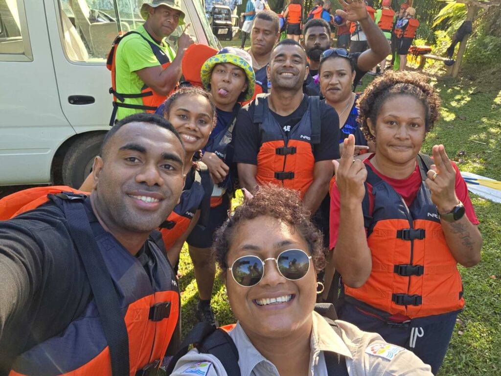 a group of people wearing orange lift jackets and having fun with the photographer they are part of the ranger group