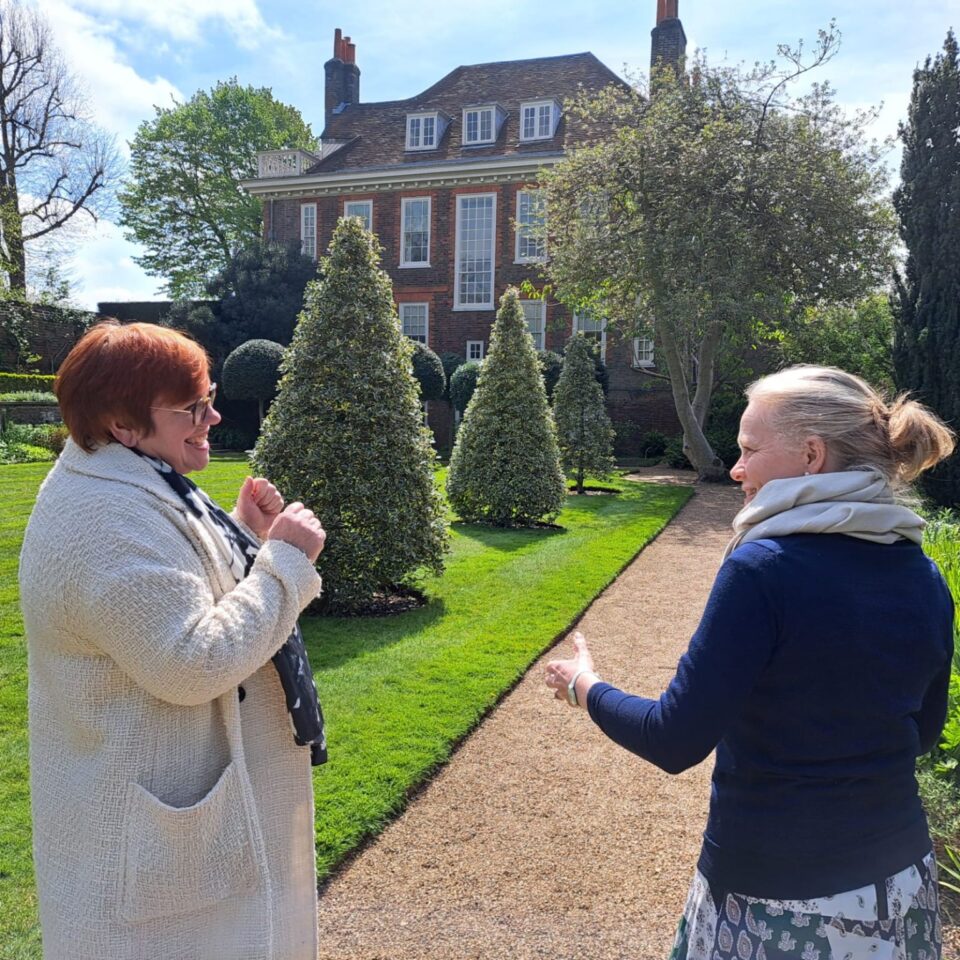 two women walking around a garden in a heritage setting having a conversation