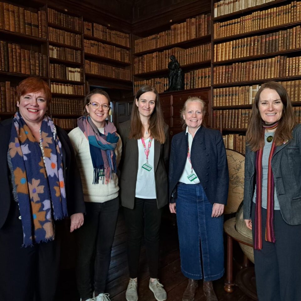 Marie Lavandier with 4 women in the library at Ham House. It is a heritage setting with low lighting and many shelves of historic books