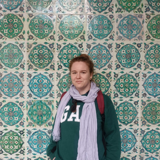 a photo of a young woman wearing a lilac scarf with a vibrant green and blue tiled background
