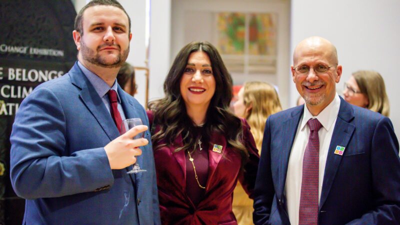 People talking at an exhibition in a high-ceilinged white room, with colourful exhibition panels
