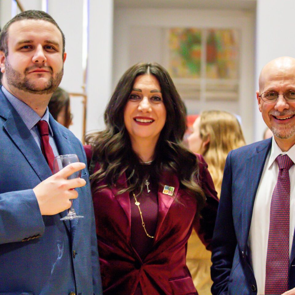 People talking at an exhibition in a high-ceilinged white room, with colourful exhibition panels