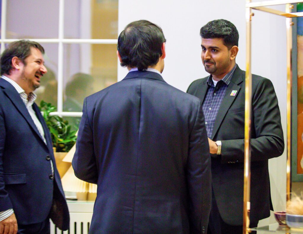 People talking at an exhibition in a high-ceilinged white room, with colourful exhibition panels
