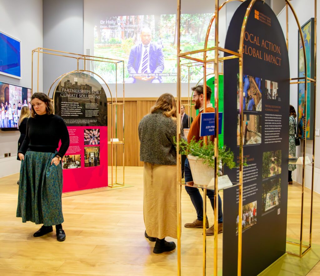 People talking at an exhibition in a high-ceilinged white room, with colourful exhibition panels
