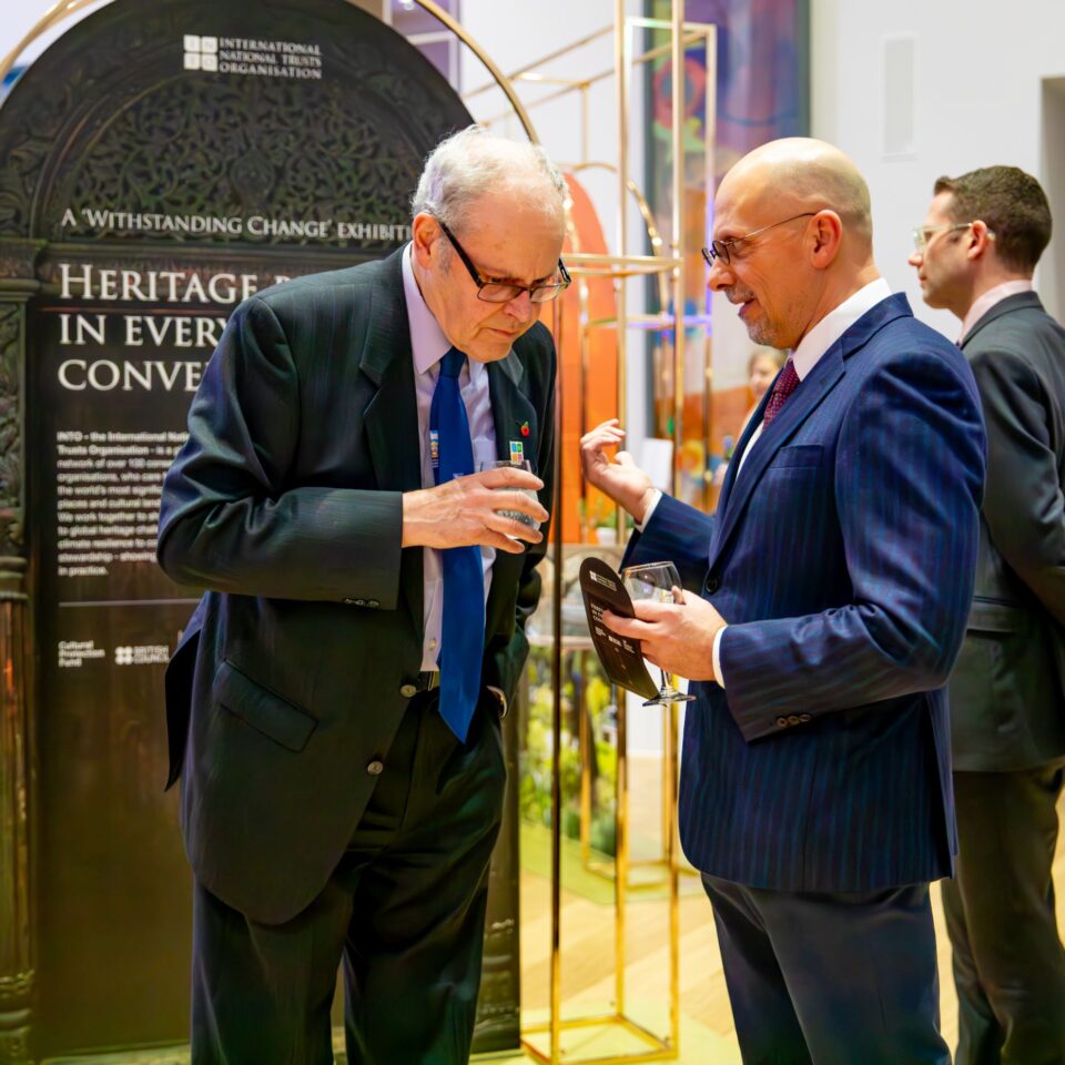 People talking at an exhibition in a high-ceilinged white room, with colourful exhibition panels