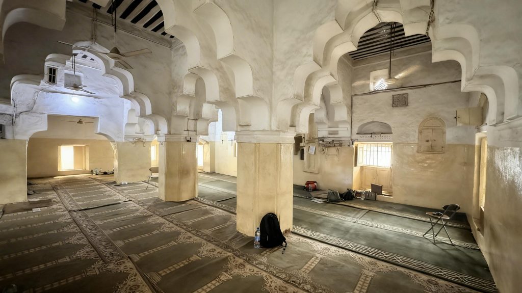 interior of a mosque in Zanzibar with elaborate stone arches and prayer rugs