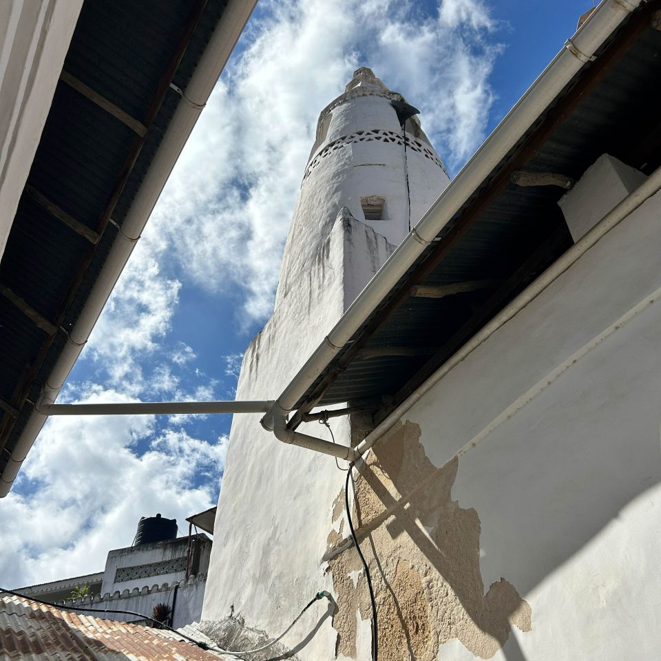 View of the iconic minaret from inside the mosque courtyard showing water damage to the walls at the base.