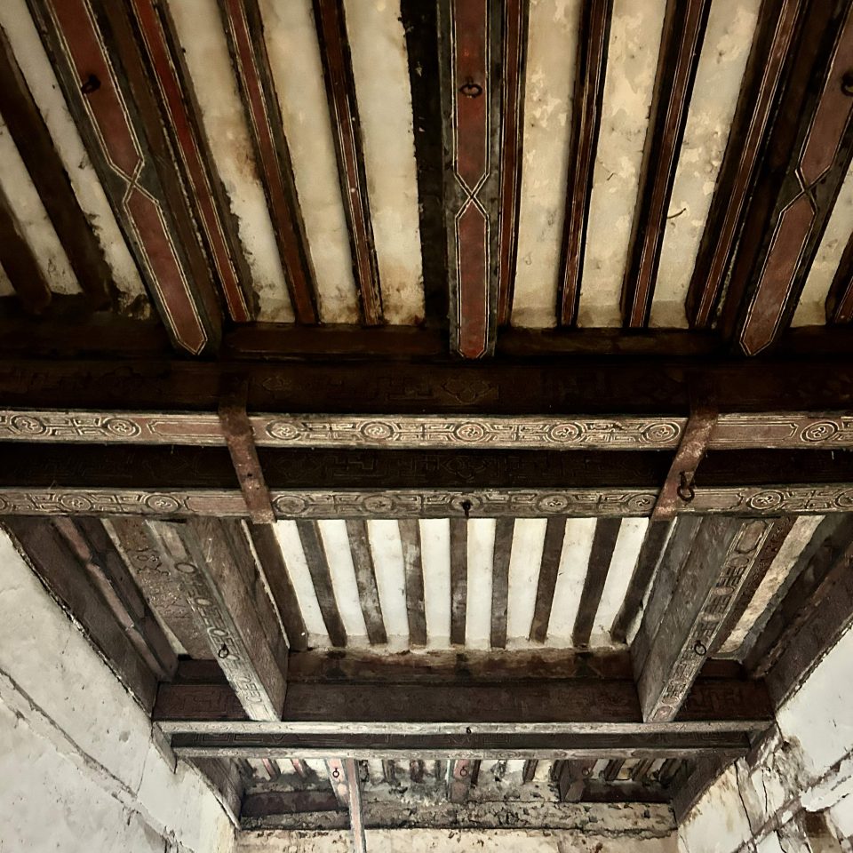 View of timber roof beams with Qur'anic inscriptions in red and black.