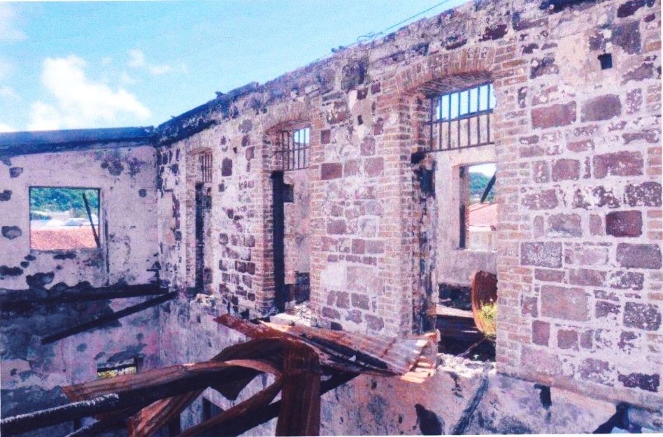 a stone wall with openings for windows and evidence of a collapsed corrugated iron roof